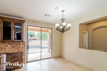 Glendale house for rent - A chandelier hangs over a kitchen island with a sink and a window.