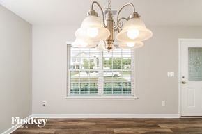 Lexington house for rent - A chandelier hangs over a window in a room with a wooden floor.