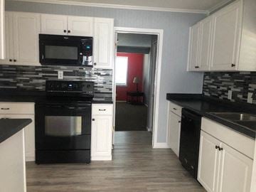 Snyder house for rent - a kitchen with black appliances and white cabinets