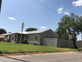 Snyder house for rent - A grey house with a white fence and a tree in front.