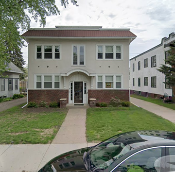 Minneapolis apartment for rent - A white house with a brown roof and a brick pillar.