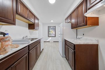 Brooklyn Center apartment for rent - a kitchen with wooden cabinets and white counters and a white refrigerator