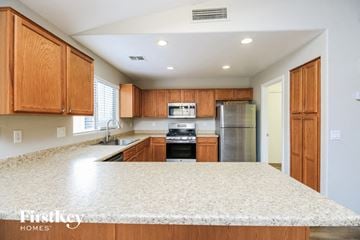 Surprise house for rent - a kitchen with wooden cabinets and a white counter top