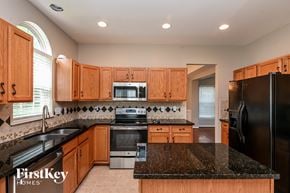 Huntersville house for rent - a kitchen with black granite counter tops and wooden cabinets