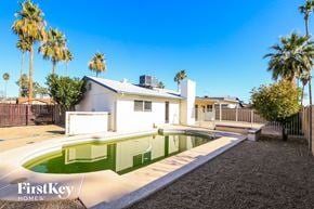 Mesa house for rent - a backyard with a pool and a house with palm trees