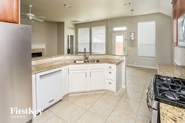 Fort Worth house for rent - a kitchen with white cabinets and granite counter tops and a stove and sink