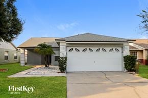 Kissimmee house for rent - a house with a white garage door and a palm tree