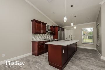 Kissimmee house for rent - a kitchen with brown cabinets and a white counter top and a sink