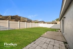 Kissimmee house for rent - a fenced backyard with a grass lawn and a white fence