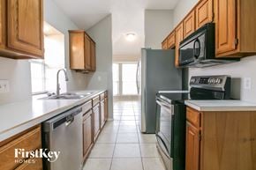 Arlington house for rent - a kitchen with wood cabinets and black appliances and white counter tops