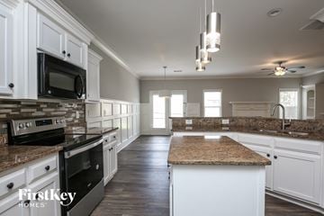 Lawrenceville house for rent - a kitchen with white cabinets and granite counter tops and black appliances