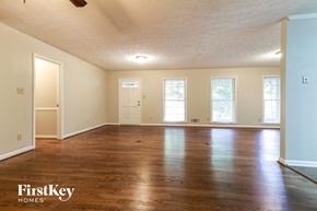 Snellville house for rent - an empty living room with wood floors and white walls