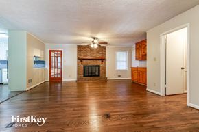 Snellville house for rent - an empty living room with a brick fireplace and wooden floors