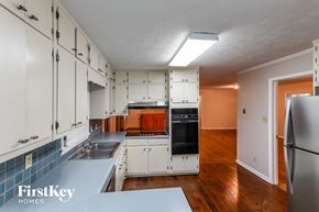 Snellville house for rent - a kitchen with white cabinets and a black stove and a refrigerator