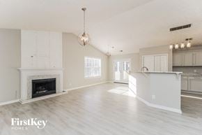 Dallas house for rent - a living room with a fireplace and a kitchen with white cabinets
