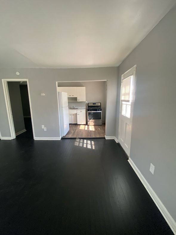 Cincinnati apartment for rent - A kitchen with white cabinets and appliances is visible through an open doorway.