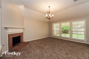 Houston house for rent - A large, empty room with a fireplace and a chandelier.