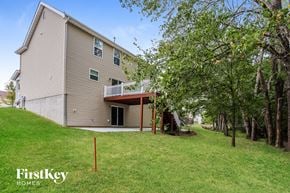 Lake St Louis house for rent - A house with a balcony is surrounded by trees and grass.