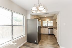 Fort Worth house for rent - A kitchen with a refrigerator, sink, and cabinets.
