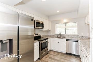 Fort Worth house for rent - A kitchen with a stainless steel refrigerator and white cabinets.