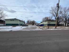 Fargo apartment for rent - A street view with houses and a car on the road.