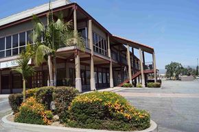 Covina apartment for rent - A building with a red roof and a palm tree in front.