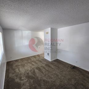 Longview apartment for rent - A carpeted room with a wall decal of a pink and white logo and the words "Rodman Realty Inc."
