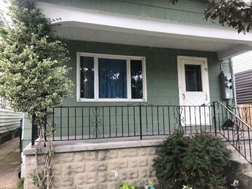 Buffalo apartment for rent - A green house with a white door and a window with a white curtain.