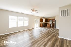 Charlotte house for rent - A spacious living room with wooden flooring and a ceiling fan.