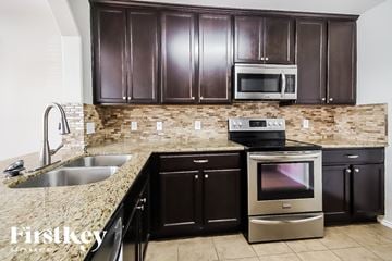 Rosenberg house for rent - A kitchen with brown cabinets and a stone backsplash.
