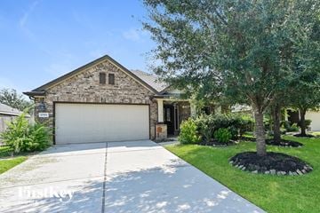 Cypress house for rent - a home with a white garage door and a tree in front of it