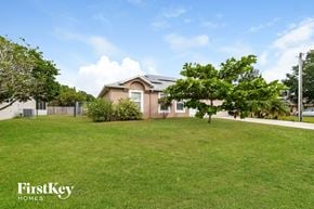 Kissimmee house for rent - a house with a lawn and trees in front of it