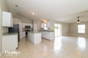 Kissimmee house for rent - a large kitchen with white cabinets and counters and tiled floors