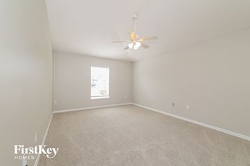 Kissimmee house for rent - a spacious living room with white carpet and a ceiling fan