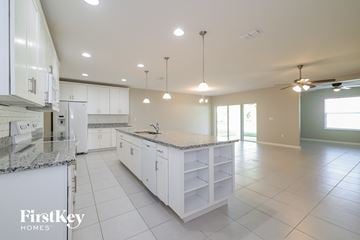 Haines City house for rent - A kitchen with white cabinets and a marble countertop.