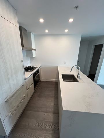 Vancouver apartment for rent - A modern kitchen with white cabinets and a marble countertop.