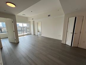 Vancouver apartment for rent - A spacious room with wooden flooring and white walls.