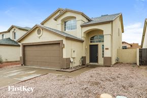Peoria house for rent - a beige house with a garage door and a gravel driveway
