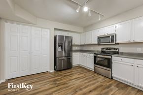 Peoria house for rent - a kitchen with white cabinets and stainless steel appliances