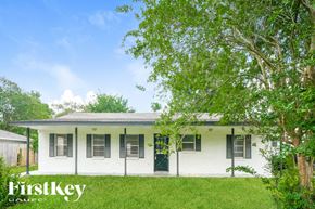 Dickinson house for rent - A white house with a green door and windows is surrounded by trees.