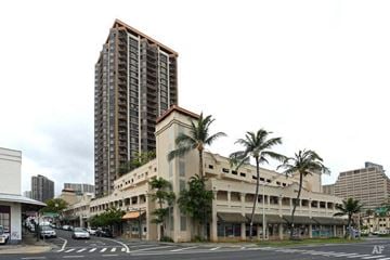 Honolulu apartment for rent - a large building on a city street with palm trees