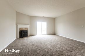 Westfield house for rent - A spacious empty room with a fireplace and a carpeted floor.