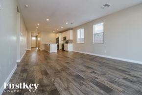 Litchfield Park house for rent - A spacious room with wooden flooring and a kitchen area in the background.