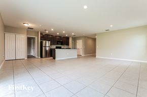 Port Charlotte house for rent - an empty living room with a kitchen with a refrigerator and a sink