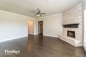 Joshua house for rent - a living room with a stone fireplace and a ceiling fan