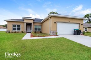 Palm Bay house for rent - A beige house with a black trash bin and a white garage door.