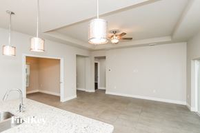Palm Bay house for rent - A spacious, empty room with a kitchen area and a ceiling fan.