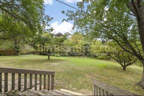 Burnsville house for rent - A wooden deck overlooks a grassy yard with trees.