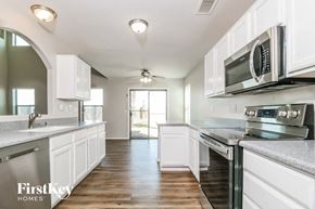 Buckeye house for rent - a kitchen with white cabinets and stainless steel appliances