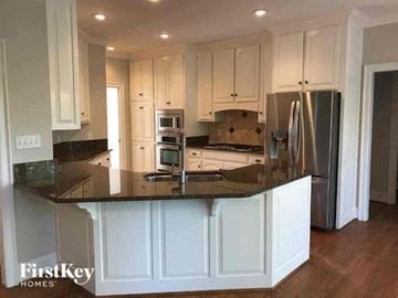 Gastonia house for rent - a kitchen with white cabinets and a black counter top